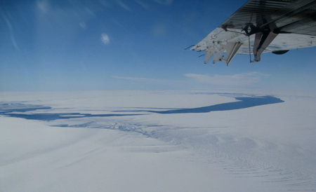 Pine Island bay and the ice shelf from the air. Past the ribbon of blue ocean is a huge iceberg that broke off last year. [Credit: G. Dossin, NASA]