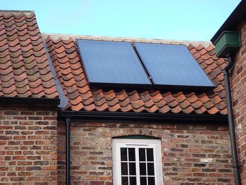 Solar thermal panels, like the ones on this rooftop, heat up under the sun’s rays and transfer the heat to water. They can harness more solar energy than high-tech photovoltaic cells. [Credit: John Moriarty, flickr.com]