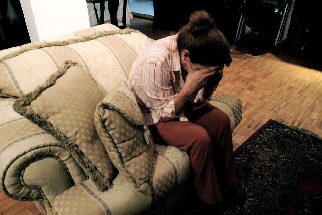 A depressed woman holds her face in her hands