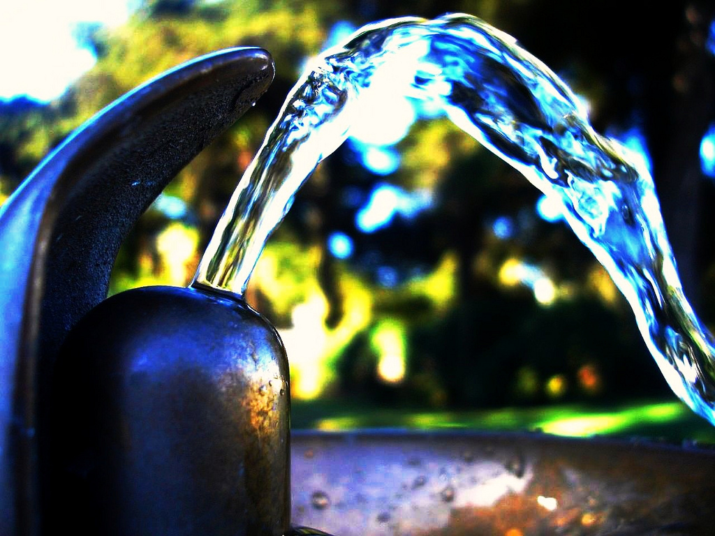 A close-up photo of water splashing out of an outdoor water fountain.