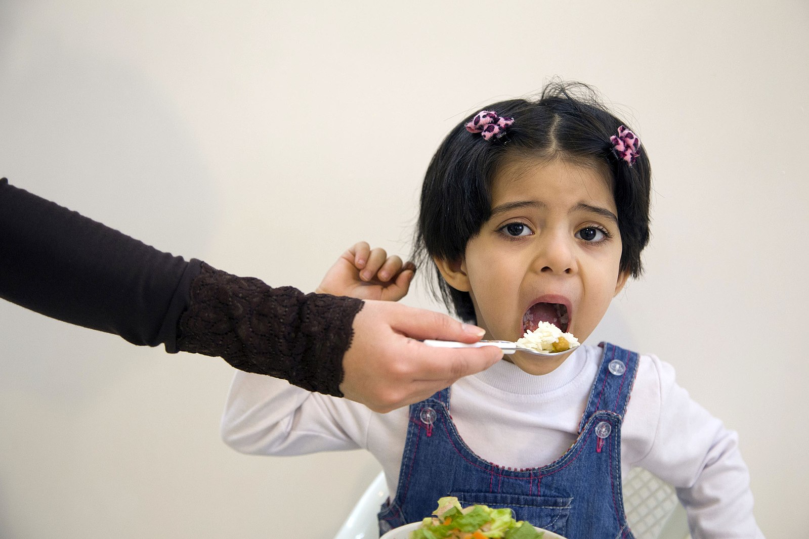 unhappy child takes a bite of food