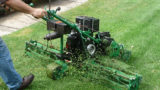 a person pushes lawnmower across grass