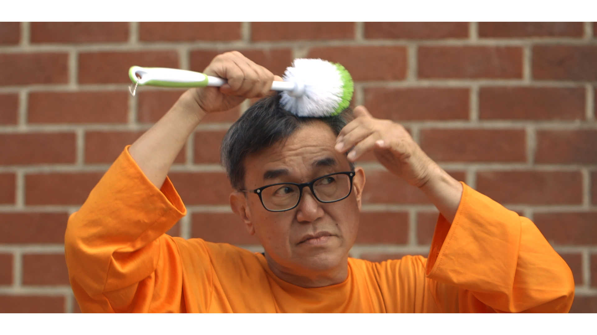 Jack Sim [Mr. Toilet] brushes his hair with a toilet wand.