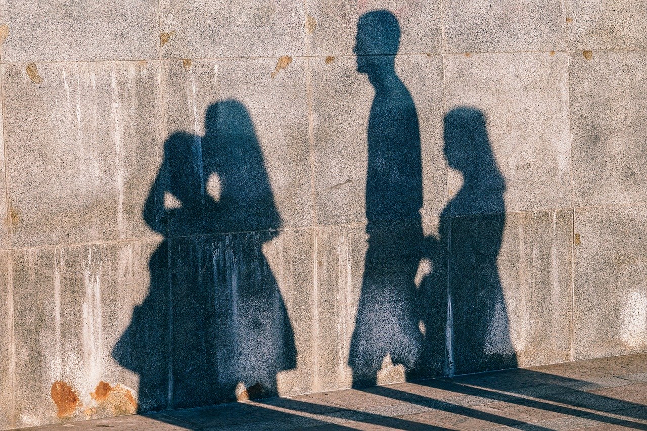 This is an image of people's silhouette against a wall on a street.