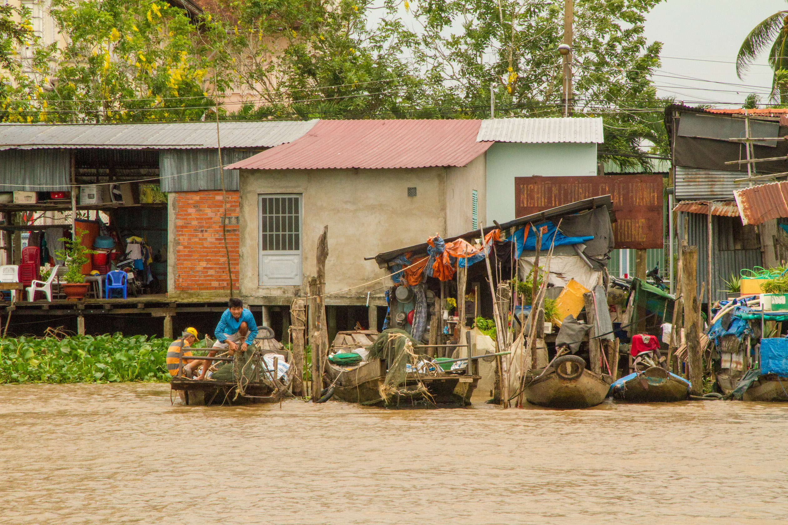 Photo of a man on a fishing boat along the Mekong River bank in Cái Bè, Vietnam