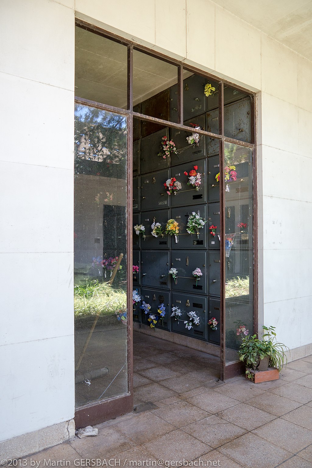 A wall of grave niches with bouquets of flowers.