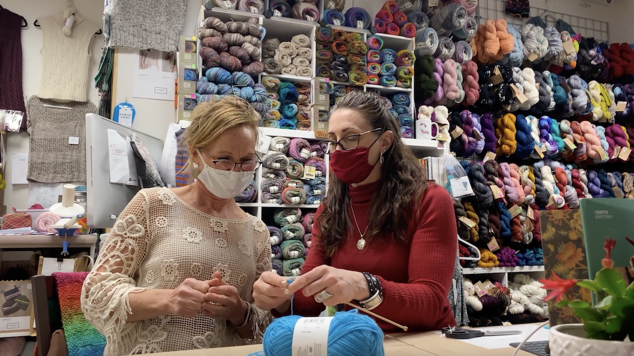 Ellen is teaching knitting to a volunteer in her shop