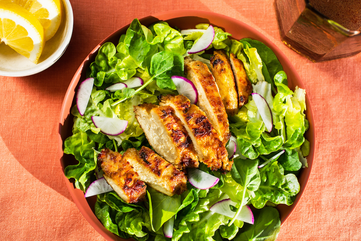A salad of leafy greens and sliced cultivated chicken