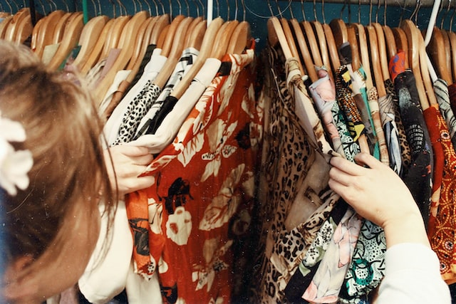 A woman looks on clothes hanging in a clothing rack