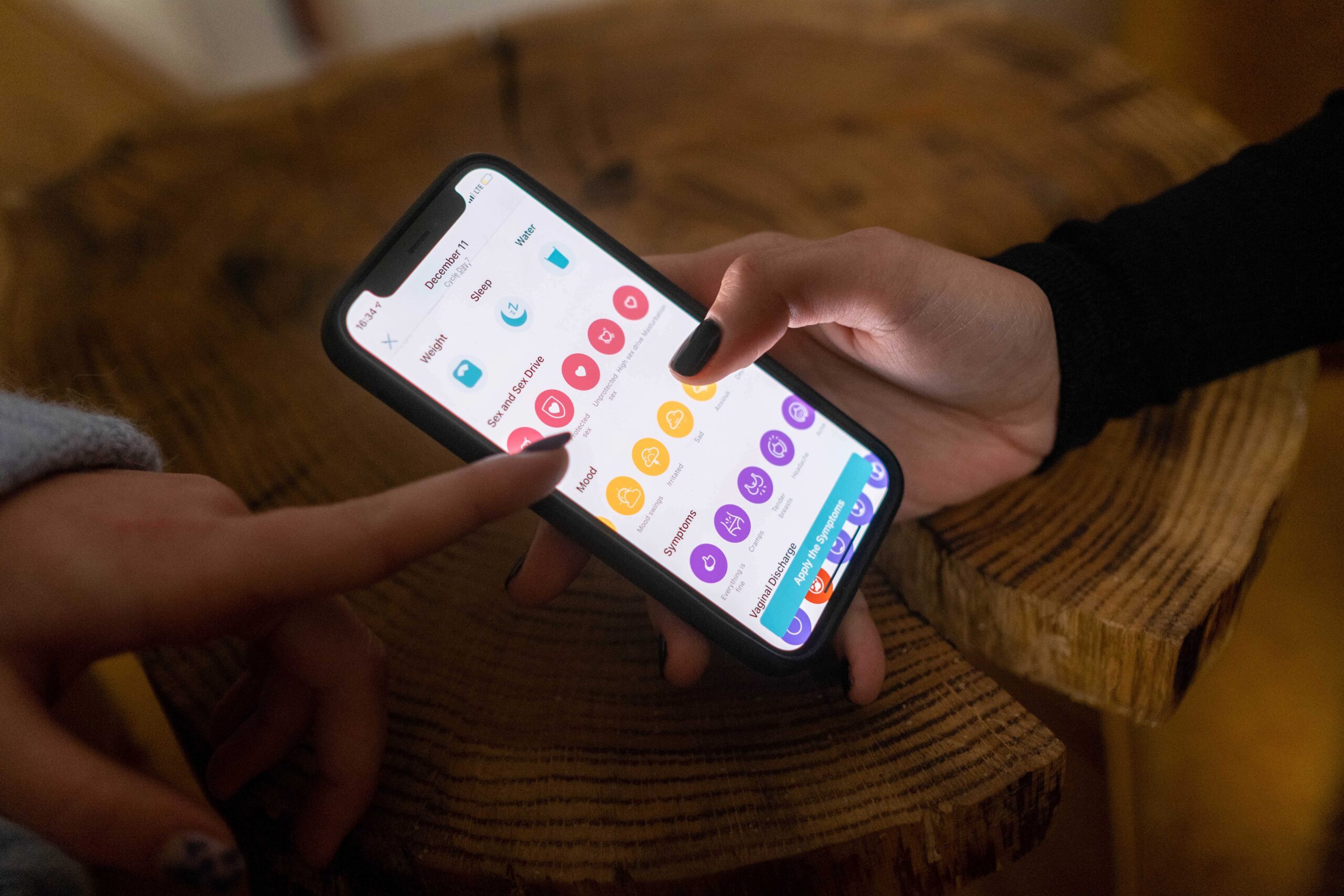 Two people point at a smartphone. A health app is on the screen.