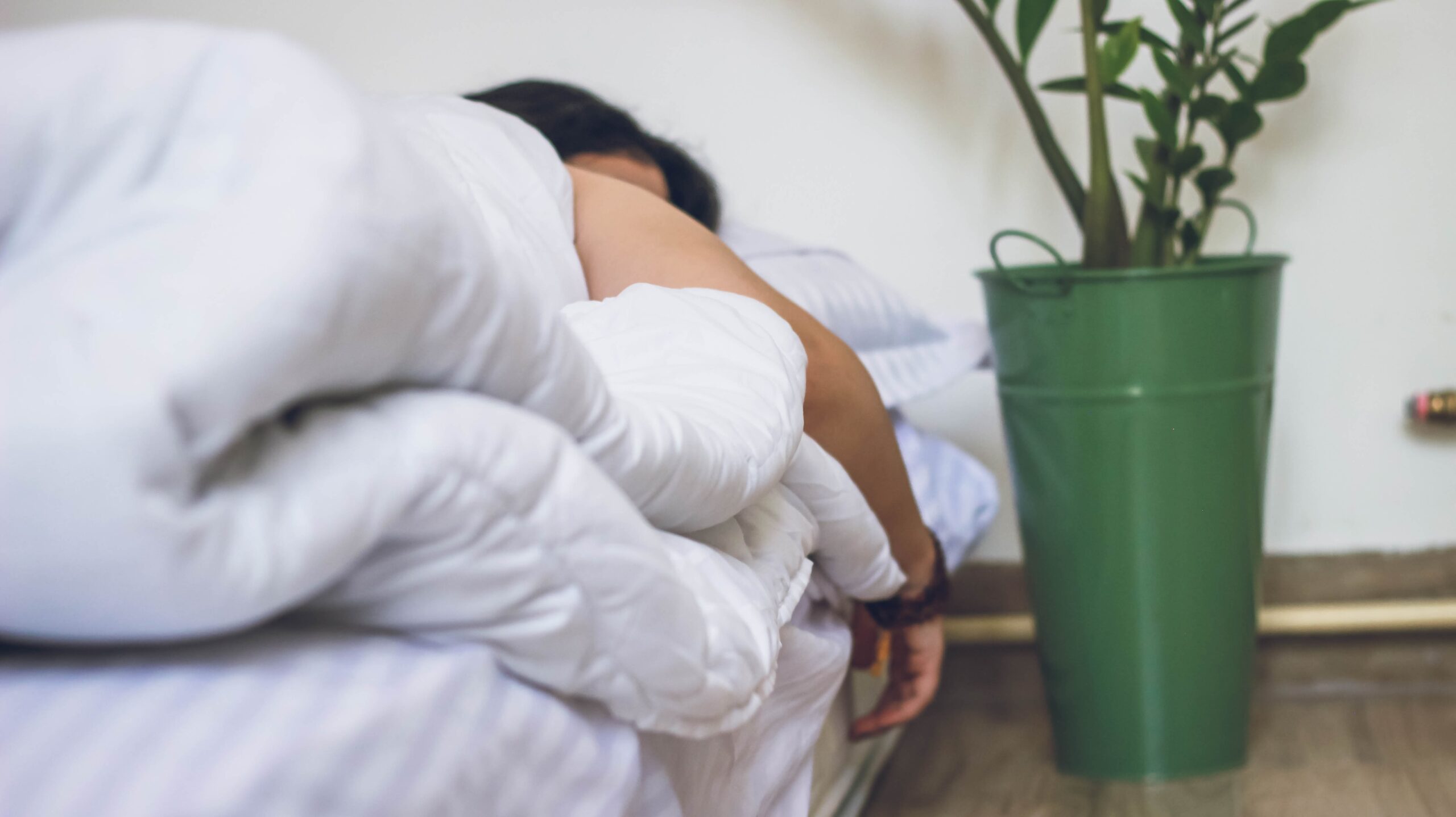 A person is fast asleep under a comforter on their bed.