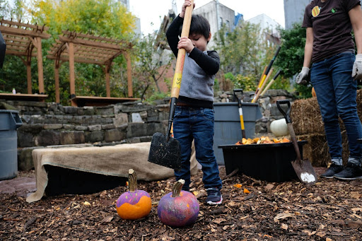 child smashing a pumpkin with a garden tool