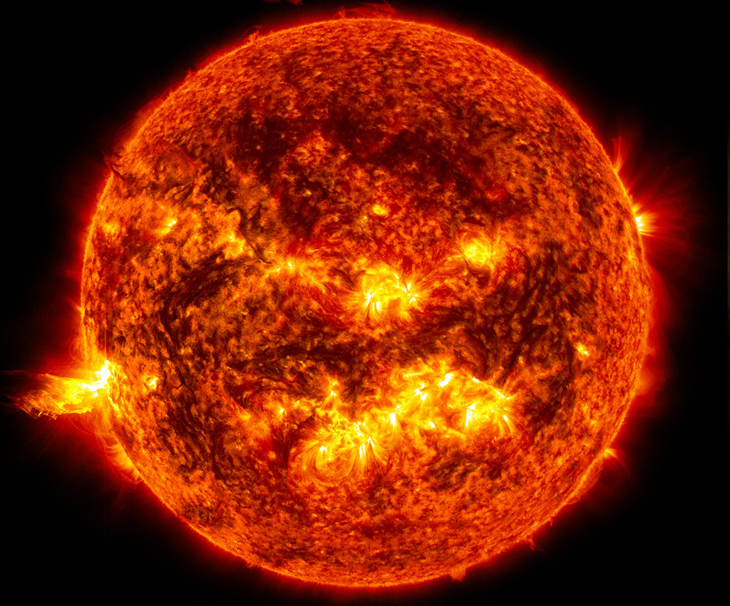 A bright-orange image of the sun in space, with brighter patches and flares around the edges