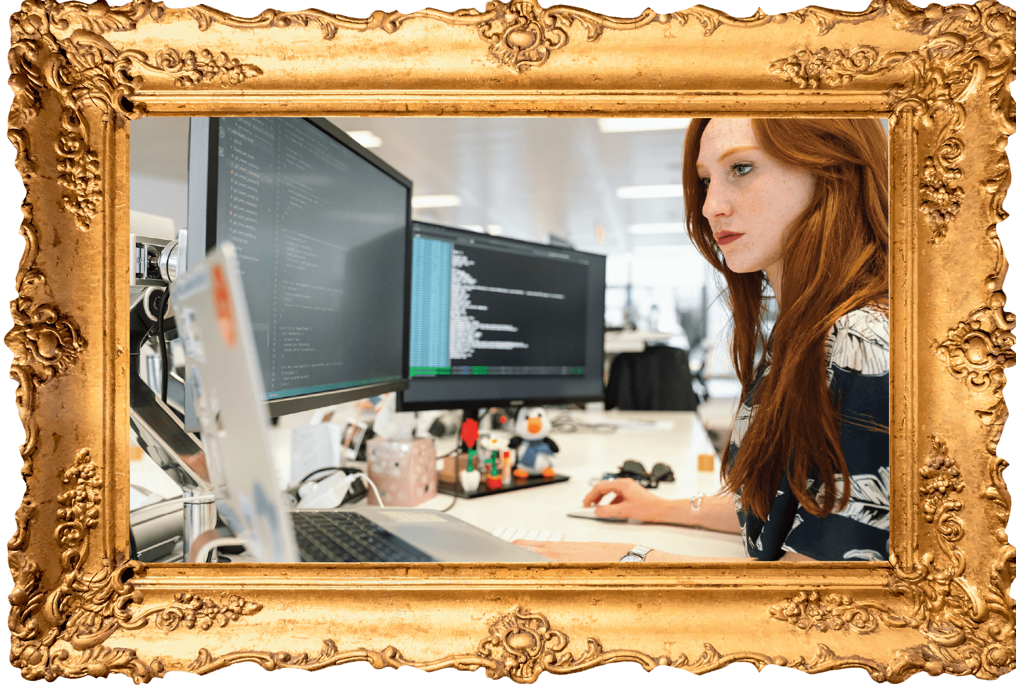 Woman sitting at the computer staring at one of two monitors.