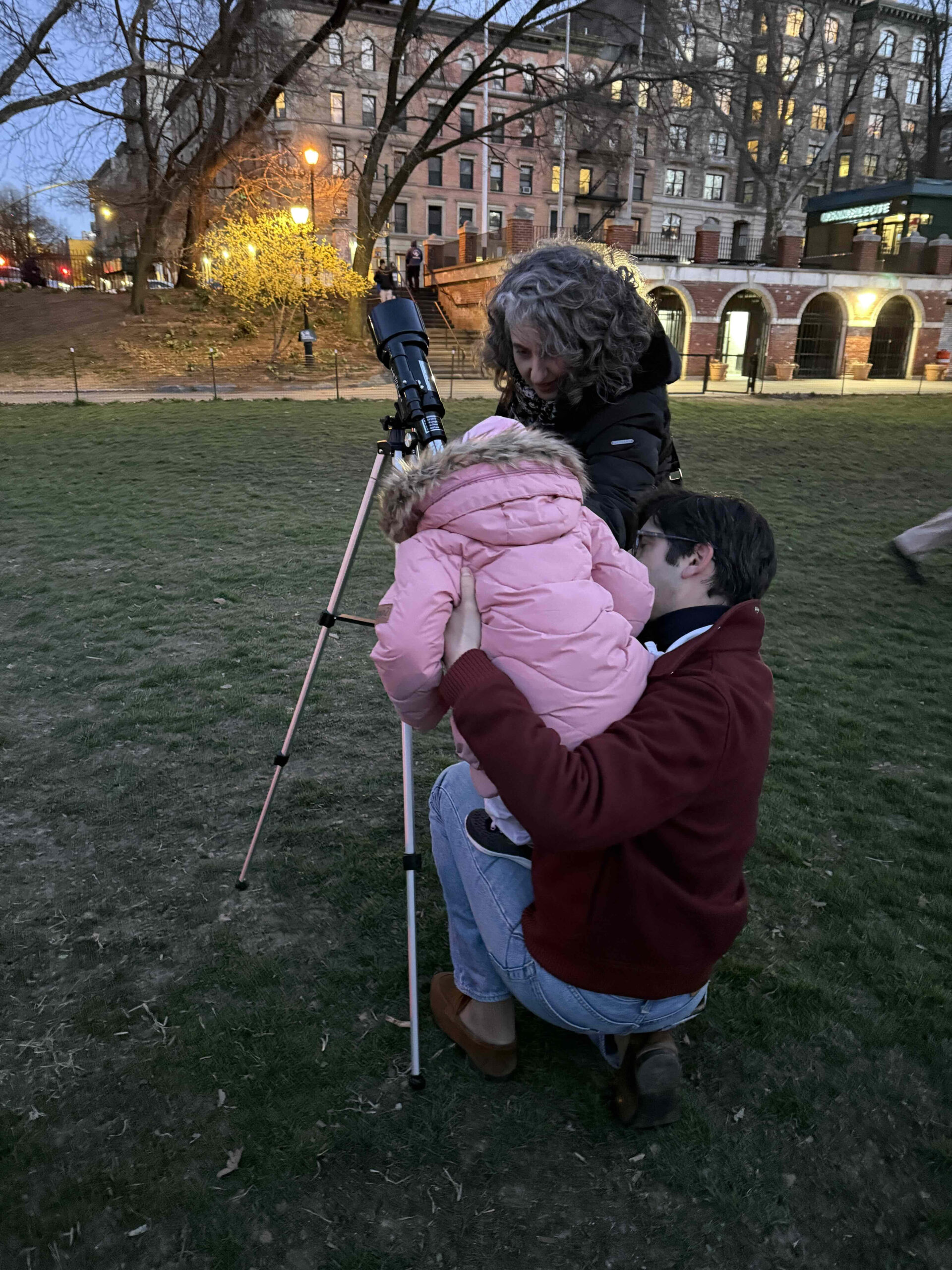 A woman and child look into a telescope.